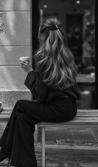 Long wavy hair styled with a clip, photographed outside a café in black and white.